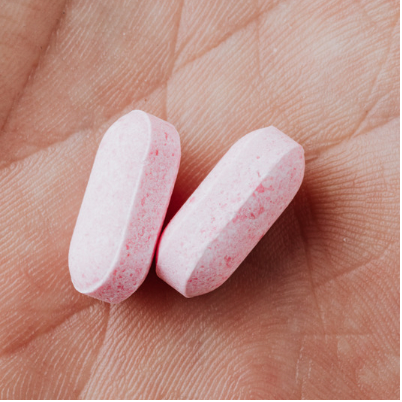 two, pink colored, contraceptive pills in an open hand