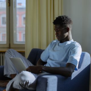 Black boy using laptop on a chair