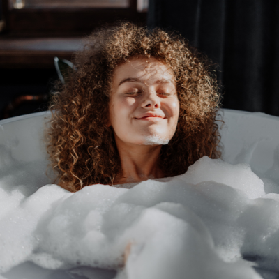 woman with curly hair in a soapy bath