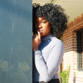 black girl leaning on the wall with curly hair