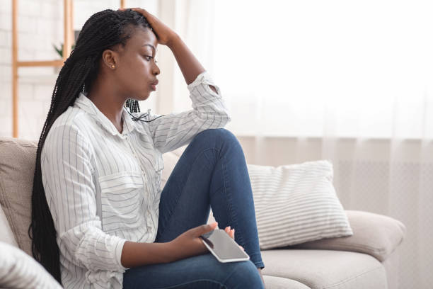 Upset Afro Girl Waiting For Important Call, Sitting On Couch With Cellphone At Home, Free Space