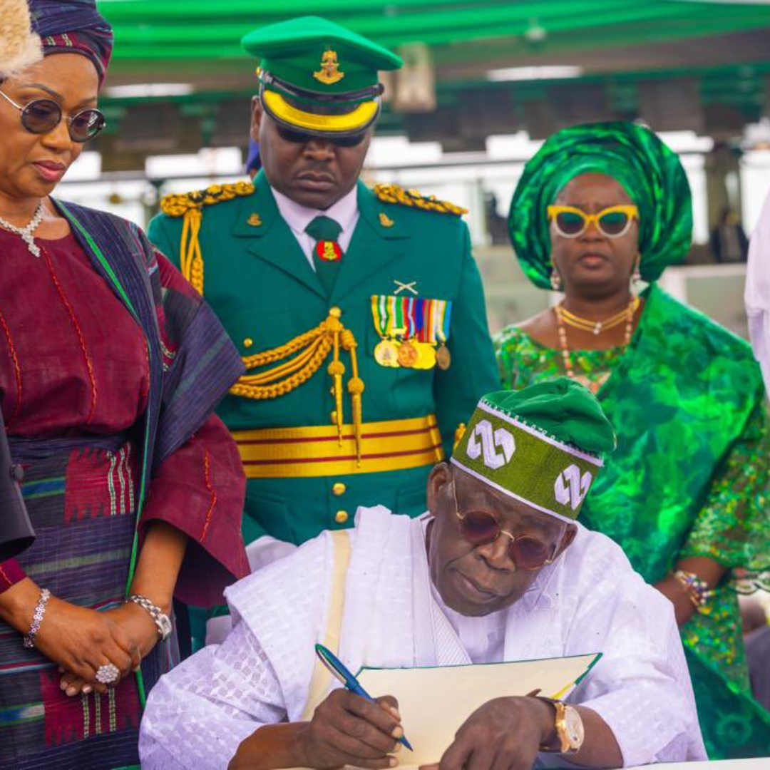Image of Bola Tinubu signing a document as he's sworn into office as president