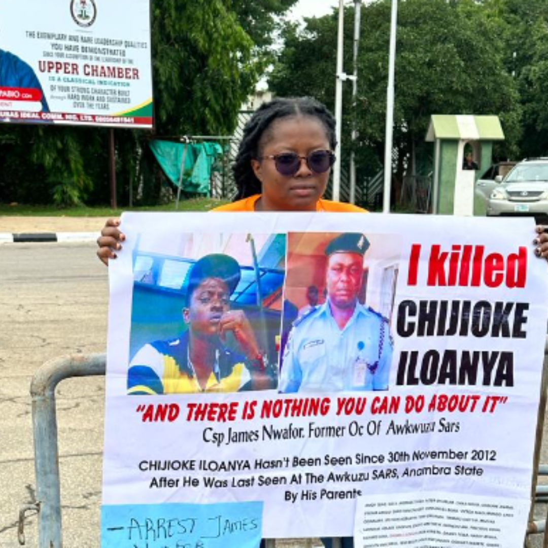 Image of Ada with banner protesting the disappearance of her brother, Chijioke.